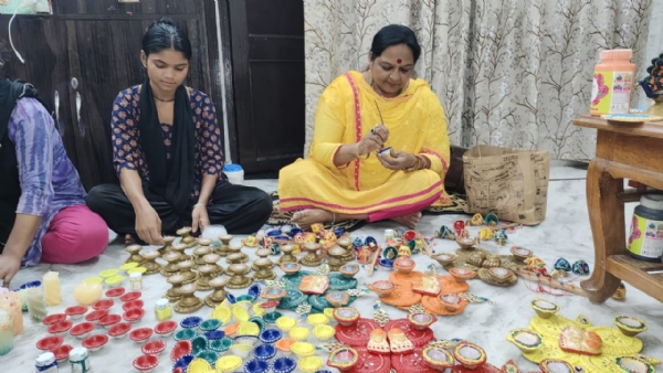 गाय के गोबर से तैयार लक्ष्मी गणेश तैयार करते हुए प्रयागराज की आभा सिंह एवं उनके सहयोगियों का छाया चित्र