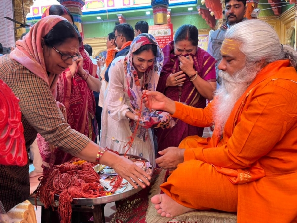 श्रद्धालुओं को धागा देते महंत शंकर पुरी श्रद्धालुओं को धागा देते महंत शंकर पुरी