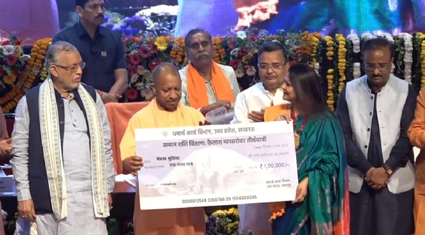 कैलाश मानसरोवर यात्री को चेक प्रदान करते सीएम योगी